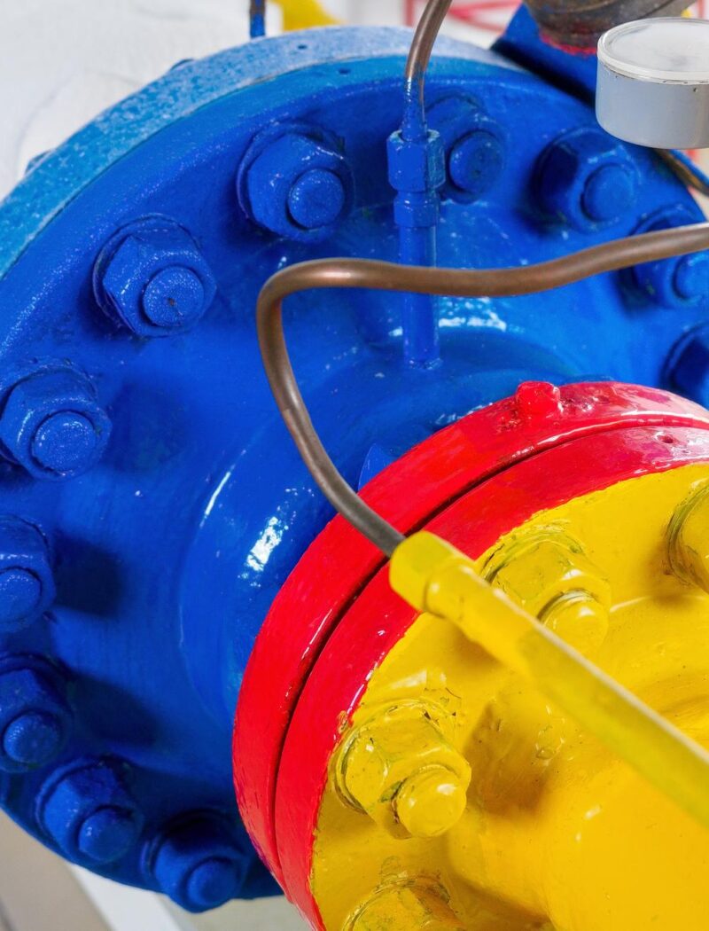Os parafusos de metal dos tubos são pintados com tinta amarela vermelha e azul Parte do equipamento de gaseificação Fundo industrial